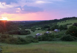 Sonnenuntergang über Hügeln und Safarizelten des Campingplatzes Les Terrasses de Dordogne in Frankreich.