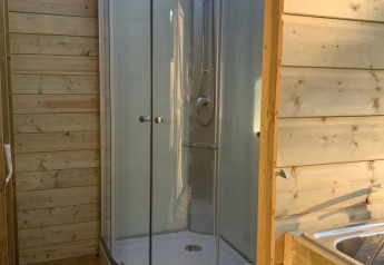 Holzverkleidetes Badezimmer im Safarizelt mit moderner Dusche, WC und Spülbecken, natürlich beleuchtet