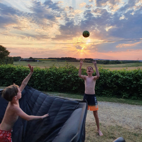 Due ragazzi giocano con una palla al tramonto al campeggio Camp Redon, villaggio vacanze in Occitania, Francia.