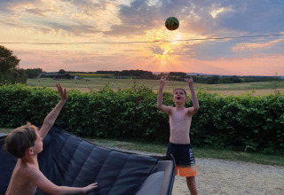 Due ragazzi giocano con una palla al tramonto al campeggio Camp Redon, villaggio vacanze in Occitania, Francia.