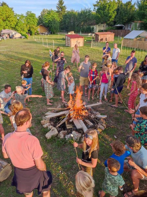 Gruppo di persone che arrostiscono marshmallow intorno a un falò presso il campeggio Camp Redon in Occitanie.