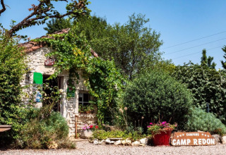 Foto della reception del campeggio Camp Redon in Occitania, Francia, circondata da piante e fiori.