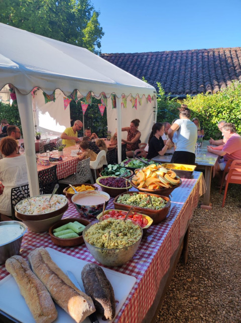 Riunione all’aperto al Camp Redon in Occitania, Francia, con tavolo da buffet e ospiti.