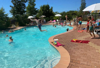Bambini e adulti si divertono giocando e nuotando nella piscina del Camp Redon in una giornata di sole in Occitania, Francia.