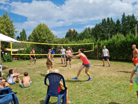 Famiglie e amici giocano a pallavolo sull’erba davanti agli spettatori al campeggio Camp Redon in Occitania.