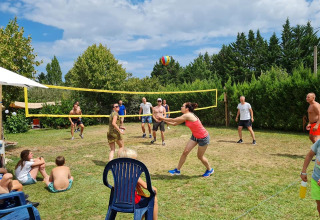 Famiglie e amici giocano a pallavolo sull’erba davanti agli spettatori al campeggio Camp Redon in Occitania.