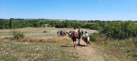 Persone camminano attraverso un prato panoramico al campeggio Camp Redon, Occitania, Francia.