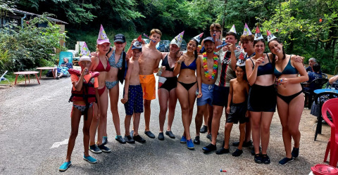 Un gruppo di giovani in costume da bagno e cappellini da festa festeggia all'aperto al Camp Redon, Occitania, Francia.