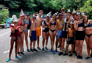 Un gruppo di giovani in costume da bagno e cappellini da festa festeggia all'aperto al Camp Redon, Occitania, Francia.