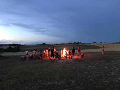 Persone riunite intorno a un falò al crepuscolo al campeggio Camp Redon nel sud della Francia, Occitania.