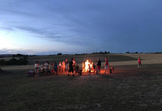 Persone riunite intorno a un falò al crepuscolo al campeggio Camp Redon nel sud della Francia, Occitania.