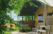 Tente safari au camping Camp Redon en France, terrasse en bois et salon extérieur sous la verdure.
