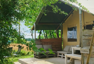Tente safari au camping Camp Redon en France, terrasse en bois et salon extérieur sous la verdure.