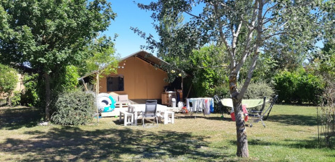 Safari tent at Campsite Camp Redon in France with outdoor seating, drying rack, and lush greenery.