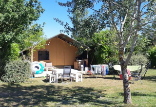 Safari tent at Campsite Camp Redon in France with outdoor seating, drying rack, and lush greenery.