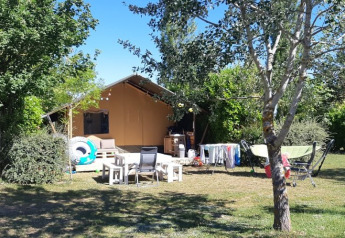 Safari tent at Campsite Camp Redon in France with outdoor seating, drying rack, and lush greenery.