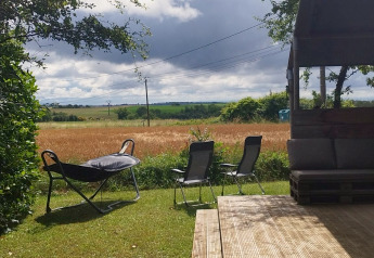 Uitzicht vanuit een Safaritent op camping Camp Redon in Frankrijk met terras, stoelen en veld.