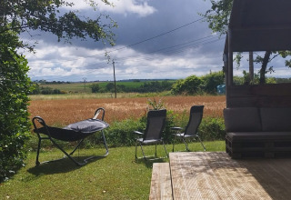 View from Safaritent at Campsite Camp Redon in France featuring a wooden deck, chairs, and open fields.