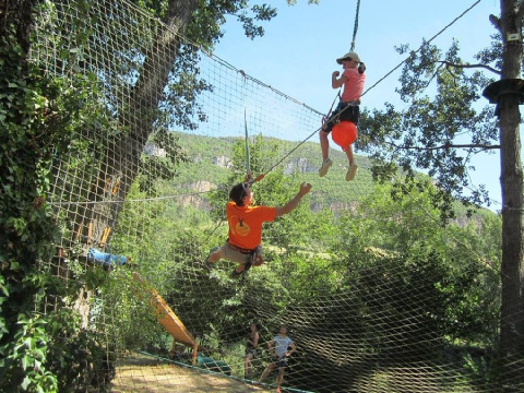 Bambini giocano su una rete da arrampicata sospesa al campeggio Camp Redon, parco vacanze in Occitania, Francia.