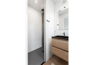 Moderne badkamer in Tiny House bij De Kremmer, Nederland, met douche en houten wastafelmeubel.