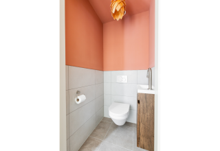 Bagno moderno in Forest villa «De Bosburcht» con wc sospeso, lavabo e particolare lampadario arancione.