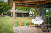 Wellness Luxe lodge a Landrijk de Reesprong, Paesi Bassi, con sedia pensile e vista sulla natura.