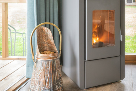 Interno del lodge Wellness Luxe con stufa a legna e secchio decorativo a Landrijk de Reesprong, Paesi Bassi.