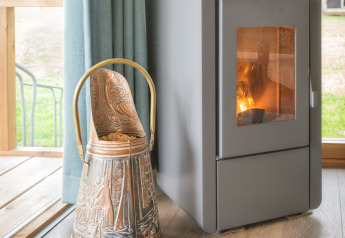 Vue intérieure du lodge Wellness Luxe avec poêle à bois et seau orné à Landrijk de Reesprong, Pays-Bas.
