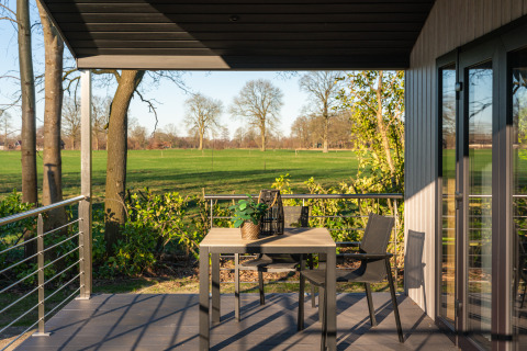Outdoor terrace with table and chairs at Weideblik met hottub, Holiday center 't Schuttenbelt, Netherlands.