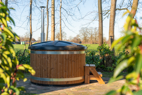 Outdoor wooden hot tub with cover and steps at Weideblik met hottub, Holiday center 't Schuttenbelt, Netherlands.