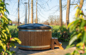 Udendørs træ-hottub med låg og stige i en grøn have ved Weideblik met hottub, Holiday center 't Schuttenbelt.