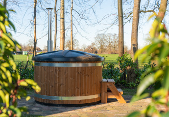Outdoor wooden hot tub with cover and steps at Weideblik met hottub, Holiday center 't Schuttenbelt, Netherlands.