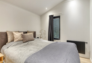 Modernes Schlafzimmer in der Weideblik-Lodge mit neutralen Farben und großem Bett im Holiday Center 't Schuttenbelt.