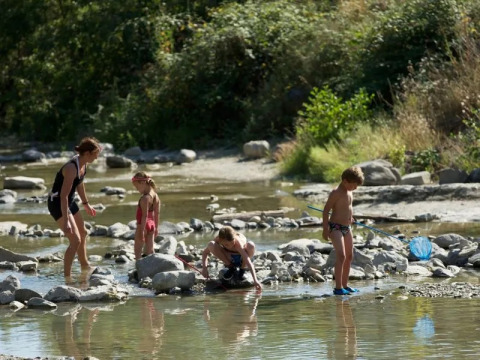 Famiglia che gioca in un fiume poco profondo al campeggio Le Moulin de Cost, in Auvergne-Rhône-Alpes, Francia.