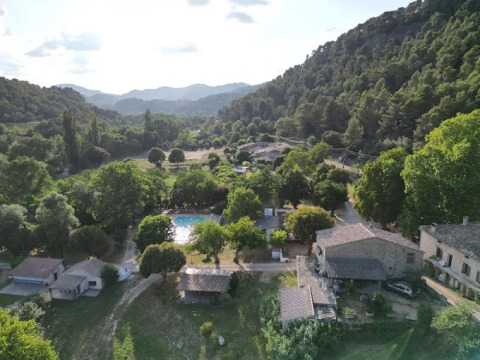 Vista aerea del campeggio Le Moulin de Cost tra alberi e colline in Alvernia-Rodano-Alpi, Francia.