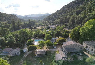 Vista aerea del campeggio Le Moulin de Cost tra alberi e colline in Alvernia-Rodano-Alpi, Francia.