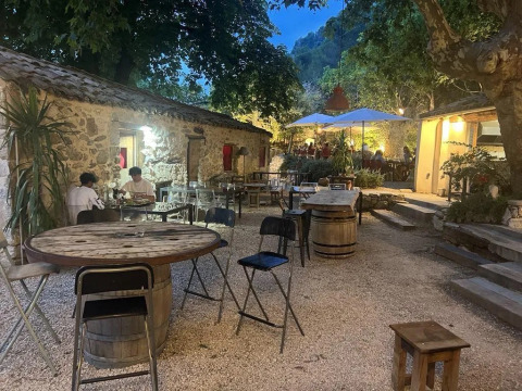 Area esterna accogliente con edifici in pietra e tavoli rustici al campeggio Le Moulin de Cost.