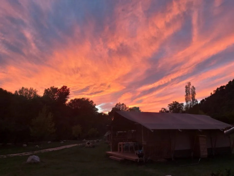 Tramonto spettacolare con nuvole arancioni e rosa sopra una tenda al campeggio Le Moulin de Cost in Francia