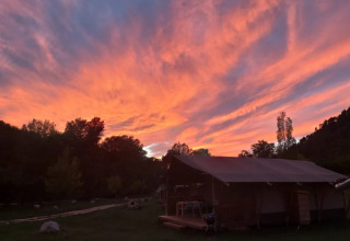 Tramonto spettacolare con nuvole arancioni e rosa sopra una tenda al campeggio Le Moulin de Cost in Francia