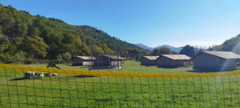 Vista di tende e colline verdi al campeggio Le Moulin de Cost, Auvergne-Rhône-Alpes, Francia in una giornata di sole