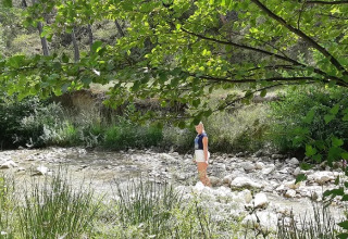 Due persone stanno in un ruscello poco profondo presso un campeggio verde in Auvergne-Rhône-Alpes, Francia.