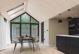 Moderne lodgeinteriør med spisebord, store vinduer og åbent køkken ved Eco Boslodge Jacuzzi, Estate De IJsvogel.
