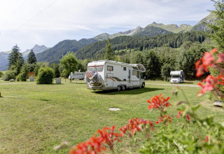 Kampeerwagens op grasveld met uitzicht op bergen bij Austriaparks Camping Arlberg in Tirol, Oostenrijk.