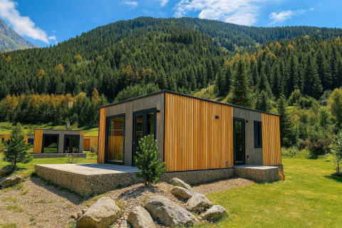 Modern cabin surrounded by lush greenery and mountains at Austriaparks Camping Arlberg, Tirol, Austria.