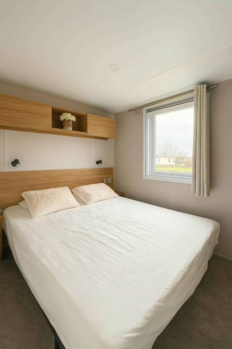 Camera da letto moderna con letto matrimoniale, finestra e mensola in legno al Vakantiehuis Celestia, Camping Papillon.