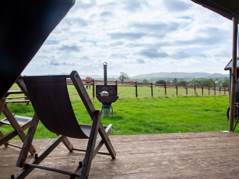 Vista dal patio con sedia a sdraio su prato verde, recinzione e colline a BoerenBed Hollings Hill, West Midlands.