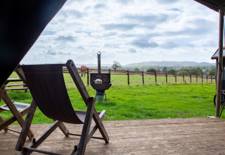 Vista dal patio con sedia a sdraio su prato verde, recinzione e colline a BoerenBed Hollings Hill, West Midlands.