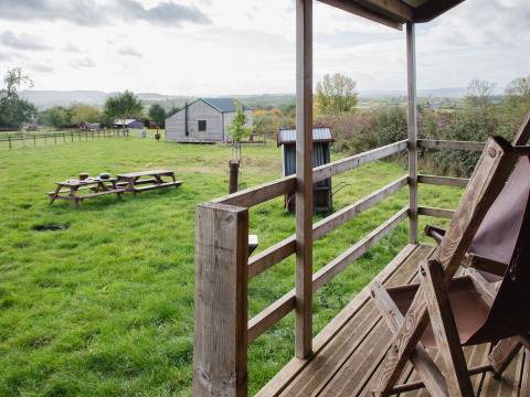 Vista da una veranda su un prato verde con tavoli da picnic presso BoerenBed Hollings Hill, West Midlands.