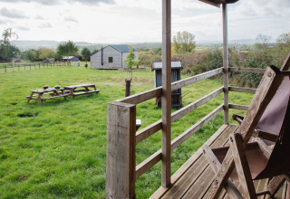 Vista da una veranda su un prato verde con tavoli da picnic presso BoerenBed Hollings Hill, West Midlands.