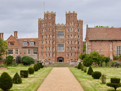 Foto af Layer Marney Tower i det østlige England, en historisk bygning og feriepark omgivet af haver.